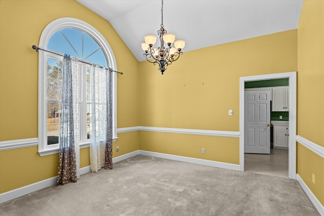 carpeted spare room featuring an inviting chandelier, lofted ceiling, and baseboards