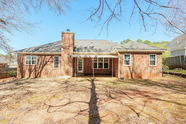 back of house with brick siding, a patio area, a chimney, and fence