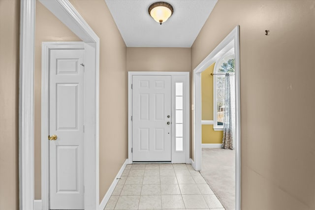 foyer with light tile patterned floors, a textured ceiling, and baseboards