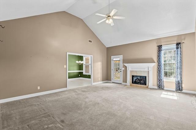 unfurnished living room with ceiling fan, a tile fireplace, high vaulted ceiling, and carpet