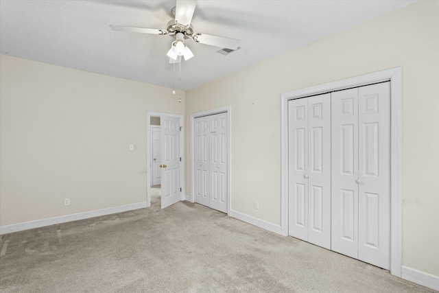 unfurnished bedroom with visible vents, baseboards, multiple closets, ceiling fan, and carpet flooring