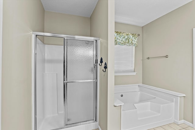 bathroom featuring tile patterned flooring, a shower stall, a garden tub, and a textured ceiling