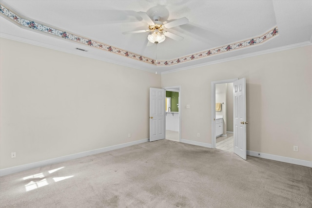 spare room with a ceiling fan, baseboards, crown molding, light colored carpet, and a raised ceiling