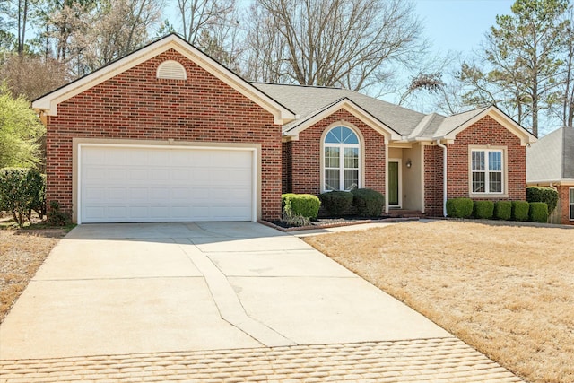 ranch-style home featuring brick siding, an attached garage, driveway, and roof with shingles