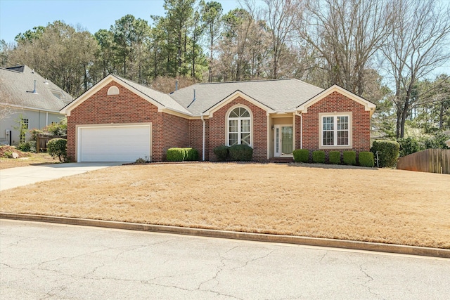 single story home with a front lawn, driveway, fence, an attached garage, and brick siding