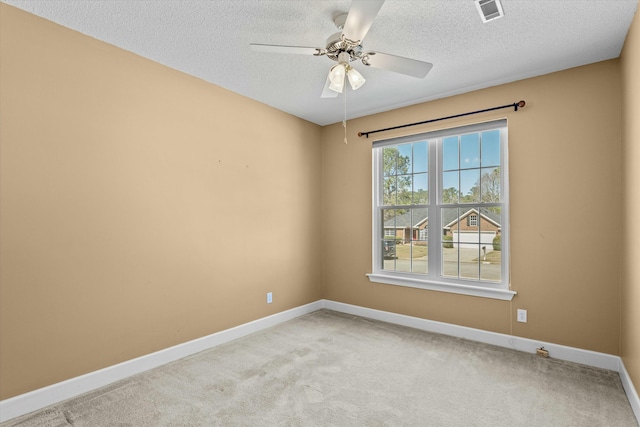 spare room featuring a ceiling fan, visible vents, baseboards, a textured ceiling, and light carpet