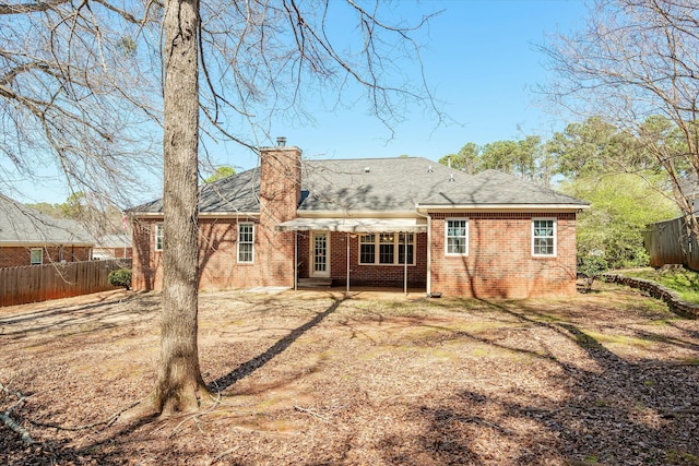 rear view of house with a patio, fence, brick siding, and a chimney