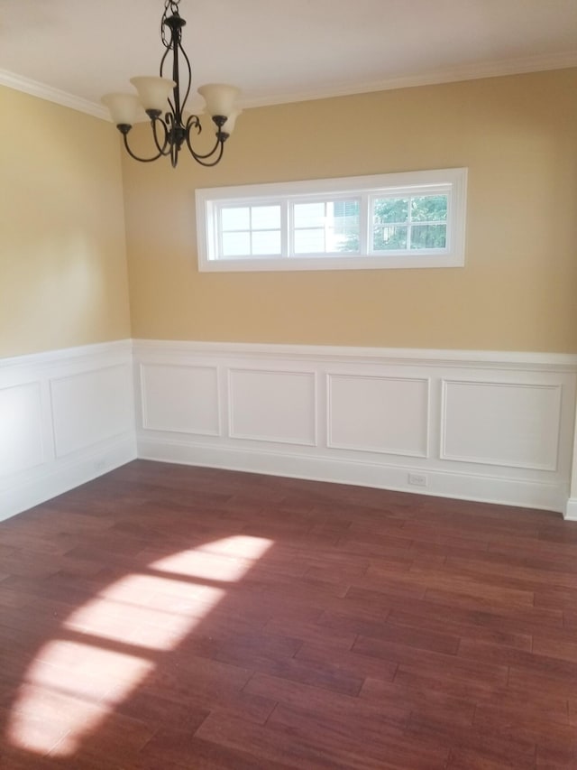 unfurnished room featuring a wainscoted wall, a chandelier, dark wood-type flooring, and ornamental molding