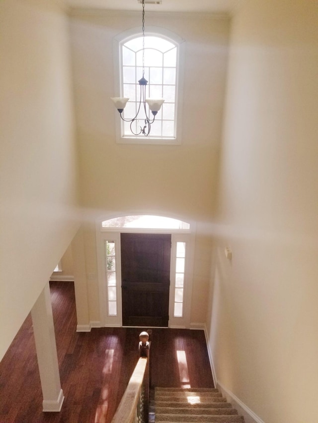 foyer with baseboards, wood finished floors, a wealth of natural light, and an inviting chandelier