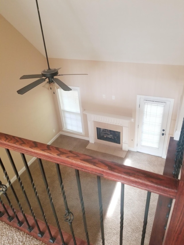 unfurnished living room with baseboards, lofted ceiling, a fireplace with flush hearth, ceiling fan, and carpet floors