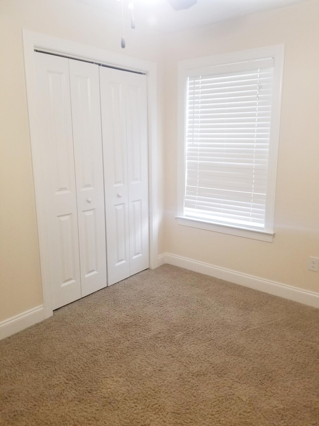 unfurnished bedroom featuring a closet, baseboards, and carpet flooring