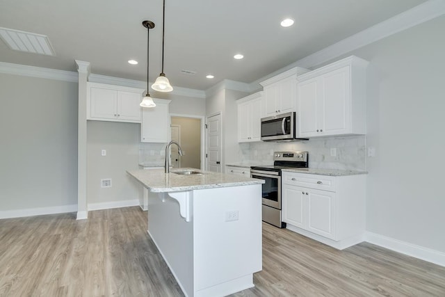 kitchen with sink, light stone counters, hanging light fixtures, stainless steel appliances, and white cabinets