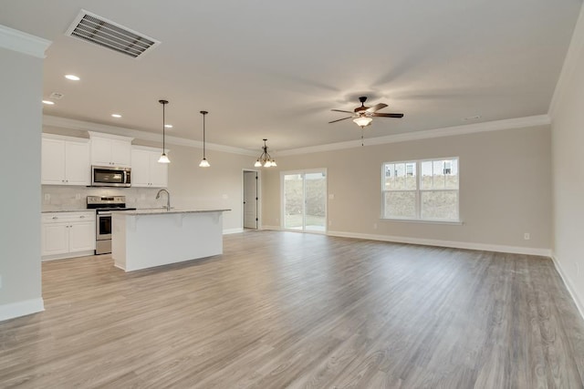 interior space with appliances with stainless steel finishes, white cabinetry, hanging light fixtures, a center island with sink, and light hardwood / wood-style flooring