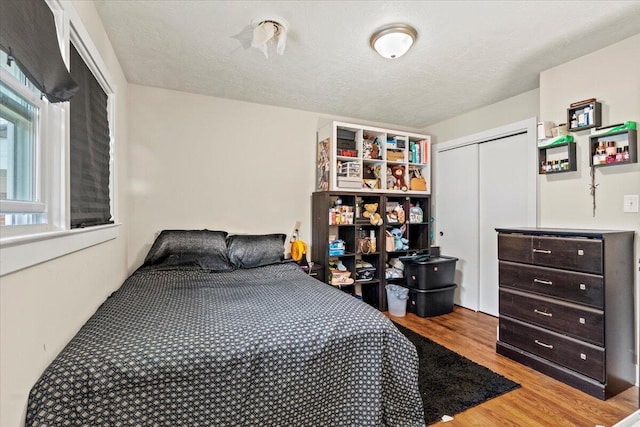 bedroom featuring light wood-type flooring, a textured ceiling, and a closet