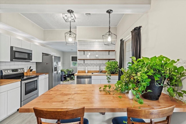 kitchen featuring a sink, appliances with stainless steel finishes, butcher block counters, and white cabinetry