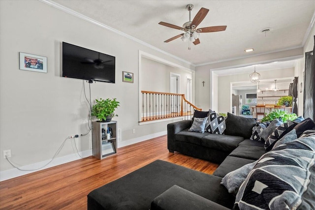 living area featuring ceiling fan, baseboards, wood finished floors, and ornamental molding