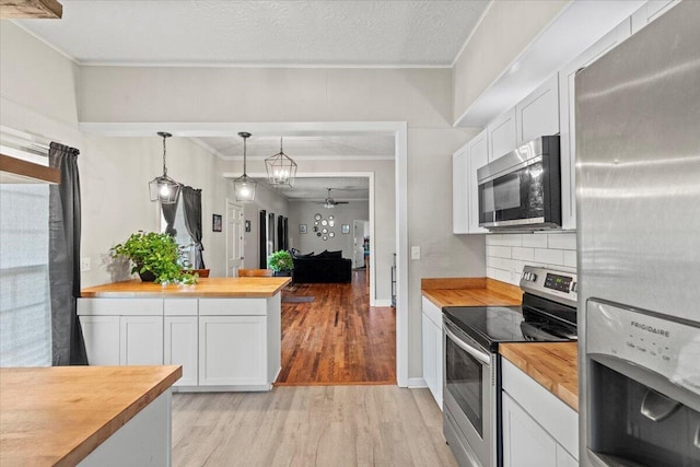 kitchen with appliances with stainless steel finishes, white cabinets, butcher block counters, and light wood finished floors