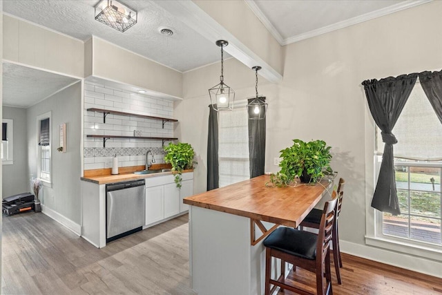 kitchen with tasteful backsplash, wooden counters, dishwasher, light wood-type flooring, and a sink