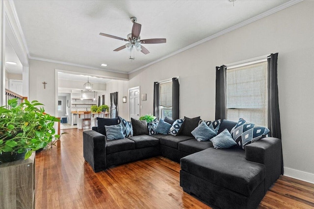 living area featuring baseboards, a ceiling fan, wood finished floors, and crown molding