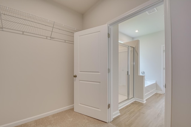 interior space with visible vents, a garden tub, a stall shower, and baseboards