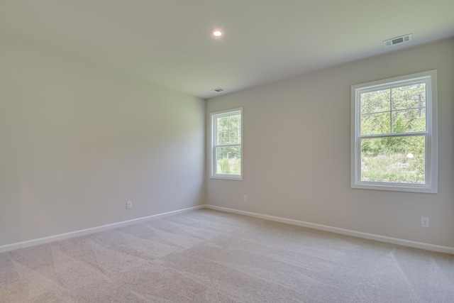 empty room featuring baseboards, visible vents, and light carpet