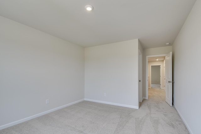spare room with recessed lighting, baseboards, and light colored carpet