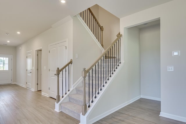 staircase with recessed lighting, wood finished floors, and baseboards