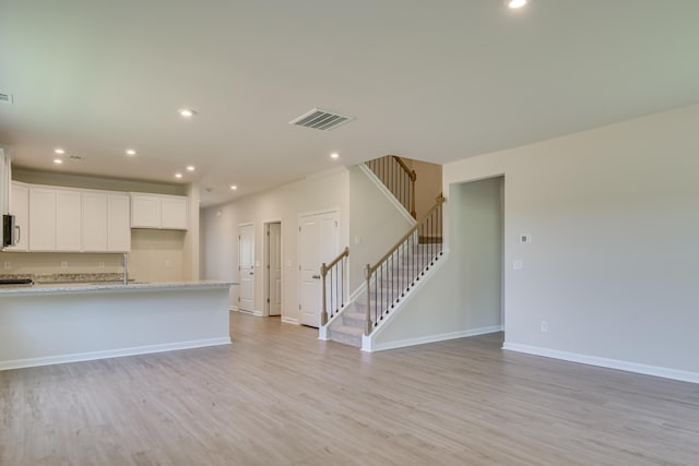kitchen featuring visible vents, light wood finished floors, baseboards, recessed lighting, and white cabinets