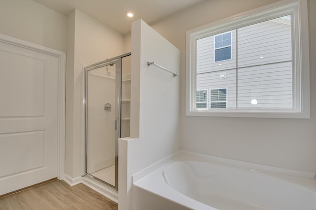 bathroom with recessed lighting, a garden tub, wood finished floors, and a shower stall