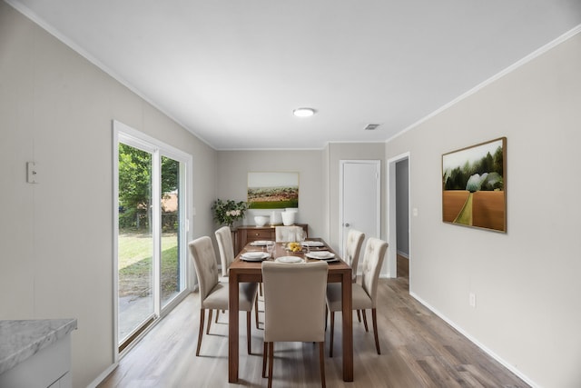 dining area featuring wood-type flooring and ornamental molding