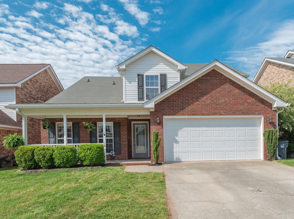 front facade featuring a front lawn, covered porch, and a garage