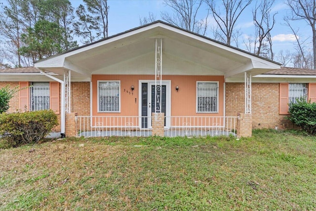 ranch-style home with covered porch and a front yard