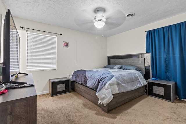 bedroom featuring ceiling fan, light colored carpet, and a textured ceiling