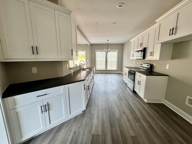 kitchen with a sink, baseboards, white cabinets, and appliances with stainless steel finishes
