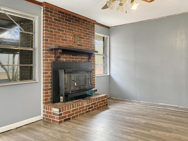 10236 S Ga Highway 23, Girard, GA 30426 - unfurnished living room featuring a wood stove, crown molding, ceiling fan, and wood-type flooring
