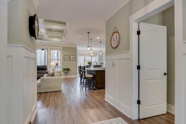 hall featuring light hardwood / wood-style flooring, beamed ceiling, coffered ceiling, and ornamental molding