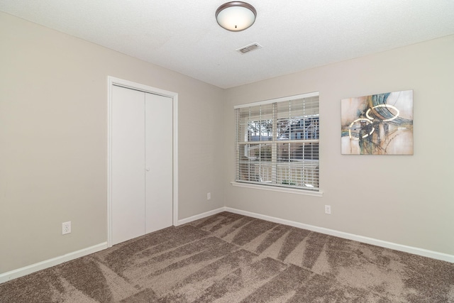 unfurnished bedroom with a closet, carpet, and a textured ceiling