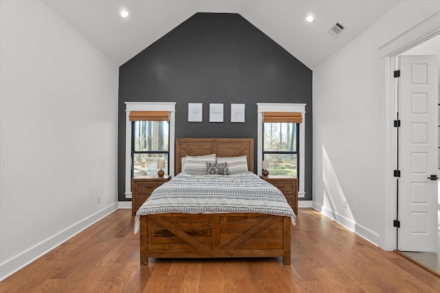 bedroom featuring visible vents, baseboards, high vaulted ceiling, and wood finished floors