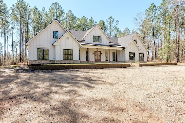 modern farmhouse style home featuring covered porch, board and batten siding, and roof with shingles