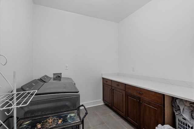 clothes washing area with light tile patterned floors, washing machine and dryer, and cabinet space