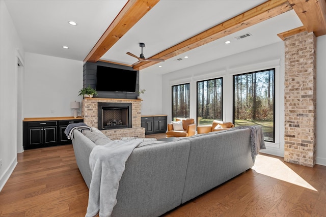 living room featuring visible vents, a brick fireplace, ceiling fan, and wood finished floors