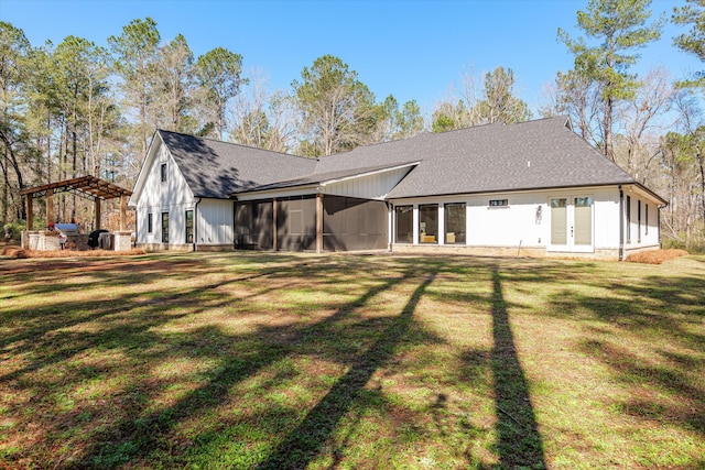 back of house with french doors, a lawn, a sunroom, and a shingled roof