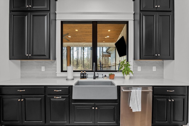 kitchen featuring stainless steel dishwasher, dark cabinetry, and a sink