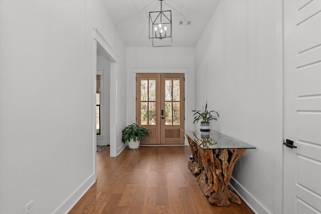 entrance foyer with an inviting chandelier, wood finished floors, french doors, and baseboards