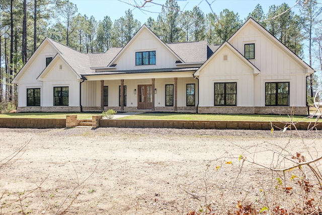 modern farmhouse featuring a porch, board and batten siding, a shingled roof, and a front lawn