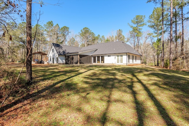 rear view of house with a lawn and a sunroom