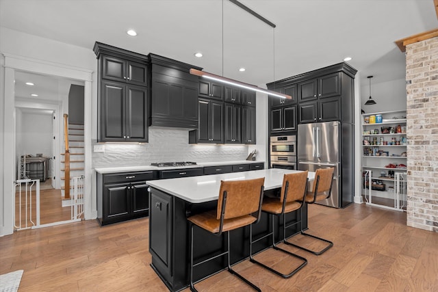 kitchen featuring stainless steel appliances, light wood-style floors, dark cabinets, and light countertops