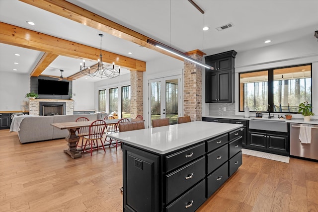 kitchen featuring dark cabinetry, a sink, light countertops, light wood-style floors, and dishwasher