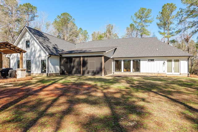 back of property with a lawn, french doors, board and batten siding, roof with shingles, and a sunroom