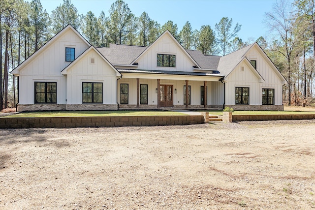 modern farmhouse style home with covered porch, board and batten siding, french doors, and roof with shingles